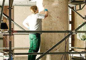 Person auf Gerüst bearbeitet Säule.