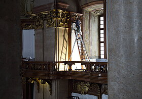 Arbeiter auf der Leiter reinigt den Stuck.