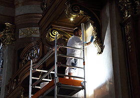 Arbeiter steht auf dem Gerüst und putzt die Wand.