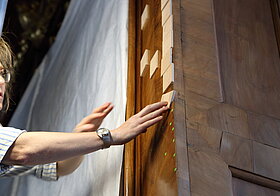 Arbeiterin platziert auf die Wand quadratische Holzblätter. 