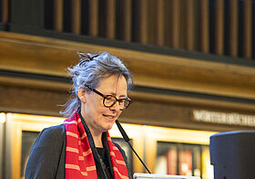 Person steht an Rednerpult.