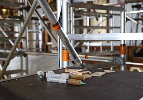 Gefüllte Kunststoffspritzen liegen vor den Holzblättchen auf dem Gerüst.