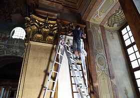 Arbeiter auf Leiter reinigt den Stuck.