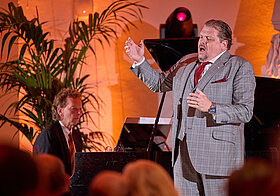 26_schade_zeyen.jpg Zwei Personen auf einer Bühne, die singen und Klavier spielen.