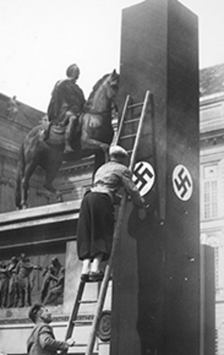 Schwarz-Weiss Bild von Männern die Hakenkreuz auf einer Säule anbringen