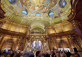 23_champagner_empfang_prunksaal.jpg Vielen Personen bei einem Champagner-Empfang in einem großen barocken Saal.