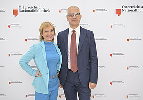 15_corporate_lunch_2023.jpg Zwei Personen posieren vor einer Logowand.