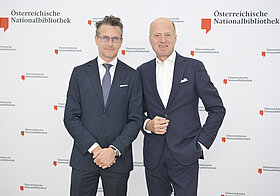 3_corporate_lunch_2023.jpg Zwei Personen posieren vor Logowand.