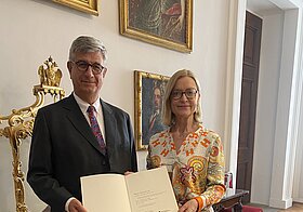 Foto von zwei Personen, die mit einer Urkunde posieren.