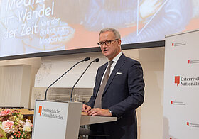 Markus_Mueller.jpg Eine Person steht an einem Podium und spricht in ein Mikrofon