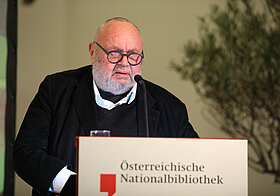 Franz_Schuh.jpg Bebrillte Person in dunkler Kleidung am Rednerpult.