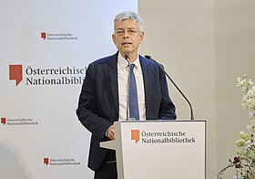 04_fetz.jpg Mann steht vor einem Podium und hält eine Rede.